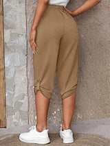 Model wearing camel roll-tab capri pants with side pockets and white sneakers for a casual outdoor look.