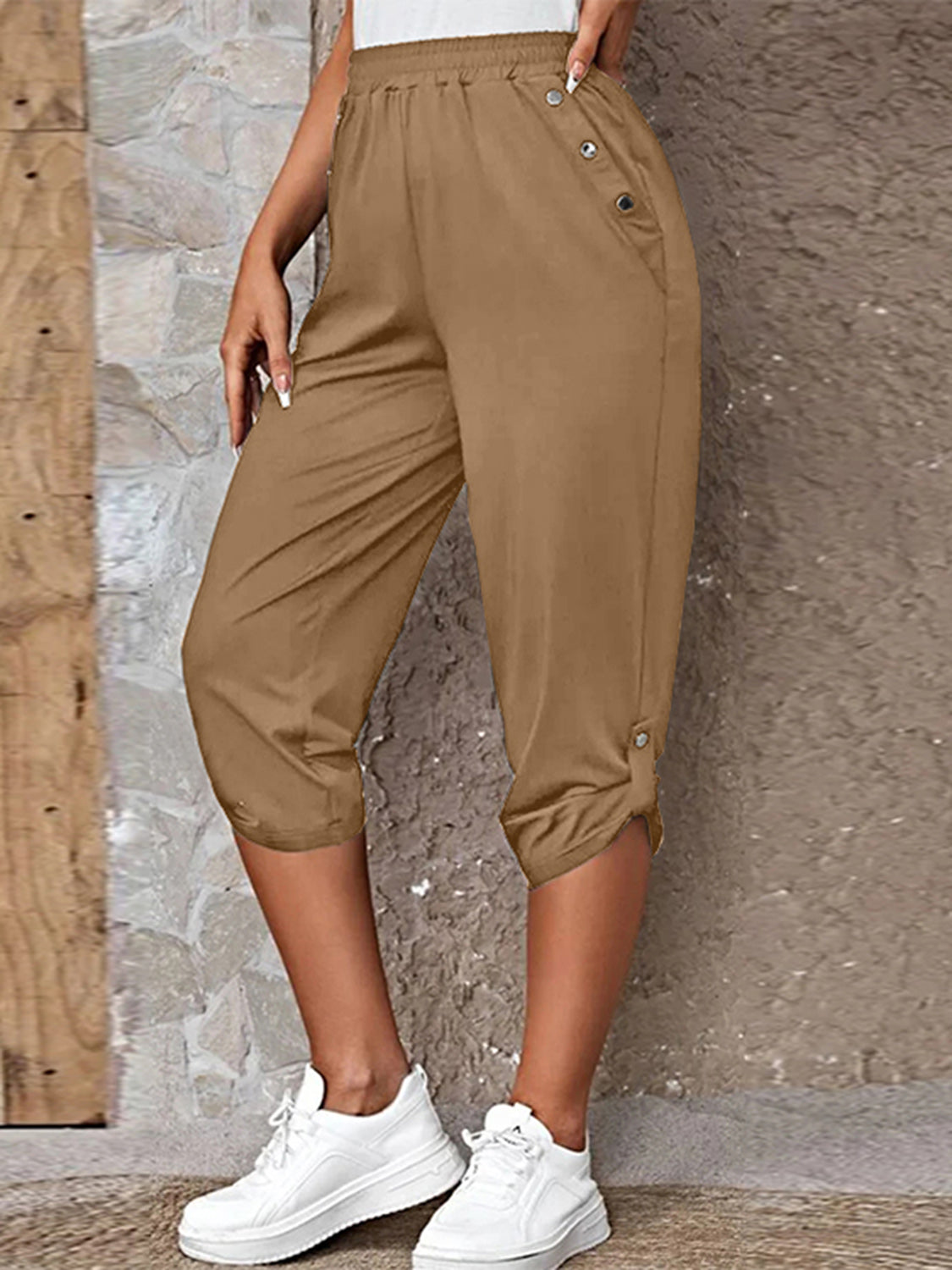 Model wearing camel roll-tab capri pants with side pockets and white sneakers for a casual outdoor look.