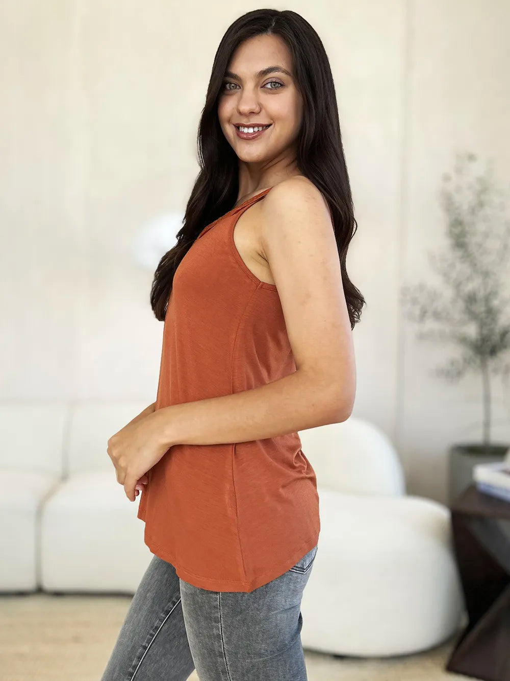 Woman wearing a caramel-colored Basic Bae lace-detail V-neck cami with delicate lace trim and cutout accents, styled with dark-wash jeans for a chic casual look.