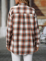 Woman wearing a caramel plaid oversized button-up shirt layered over a white top with white jeans.