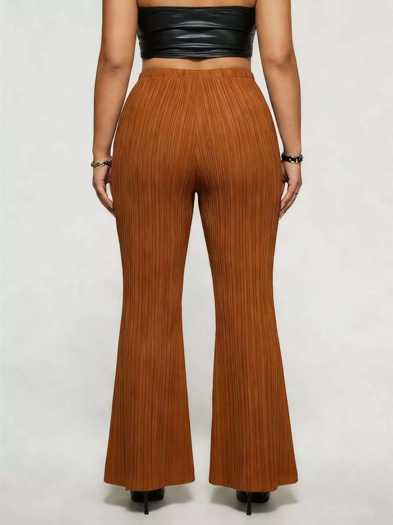 Model wearing caramel plus-size high-waisted flare pants styled with pointed-toe heels for an elegant and sophisticated look.