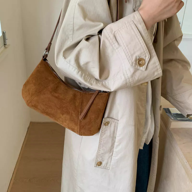 Caramel suede vintage-style shoulder bag with a minimalist silhouette paired with a neutral outfit.
