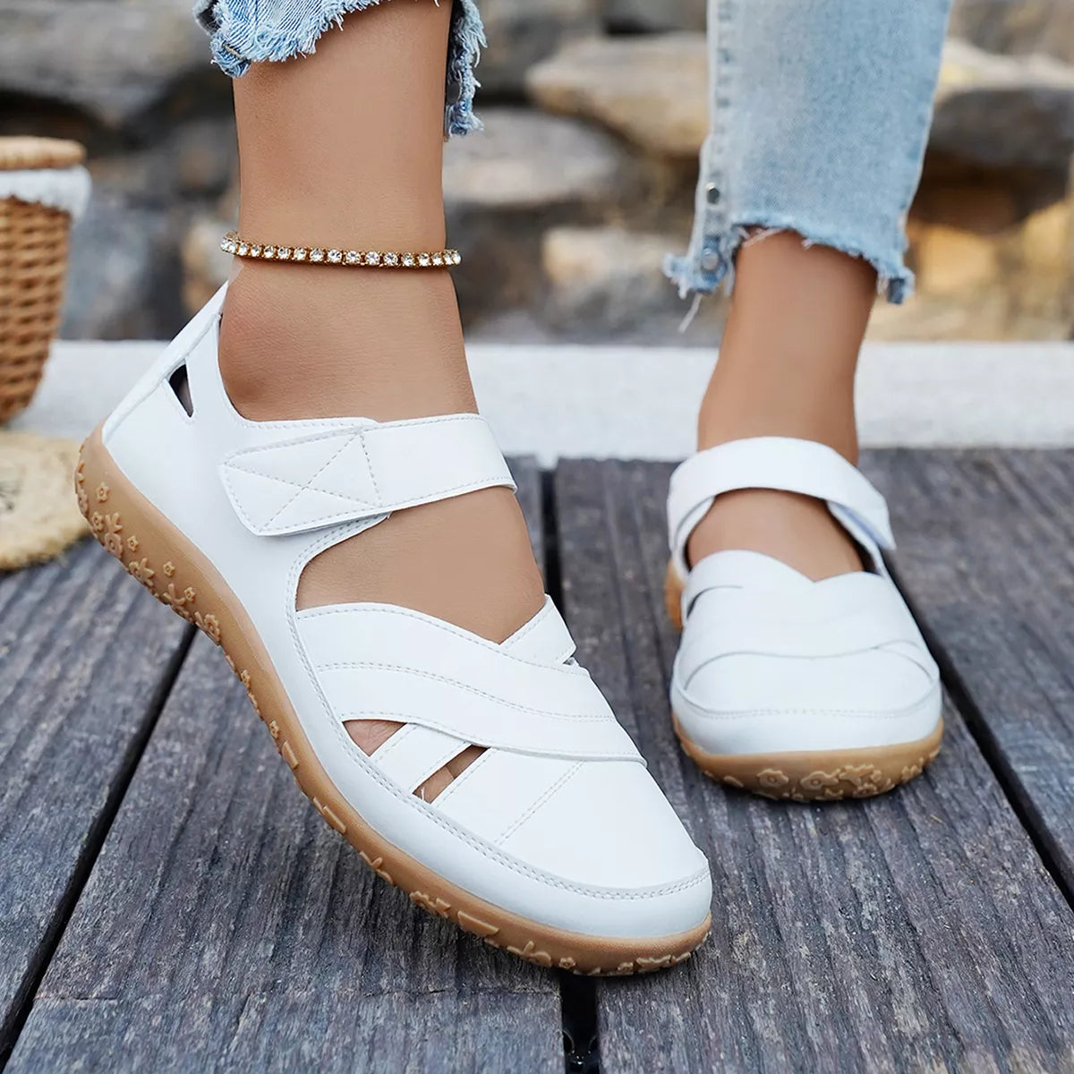 White shoes with brown soles worn by a person on a wooden surface.