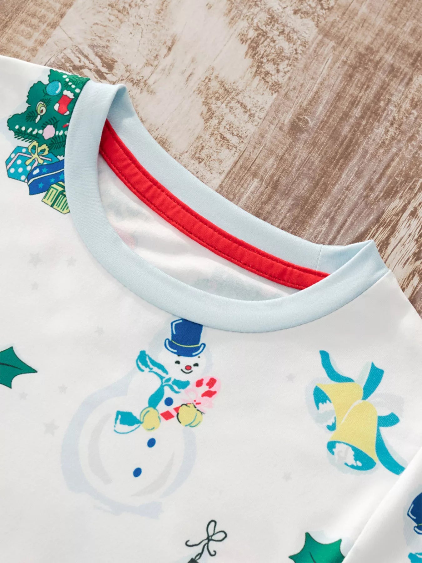 Children's white Christmas two-piece top and pants set with colorful snowmen, Christmas trees, stockings, ornaments, sleighs, and light blue cuffs.