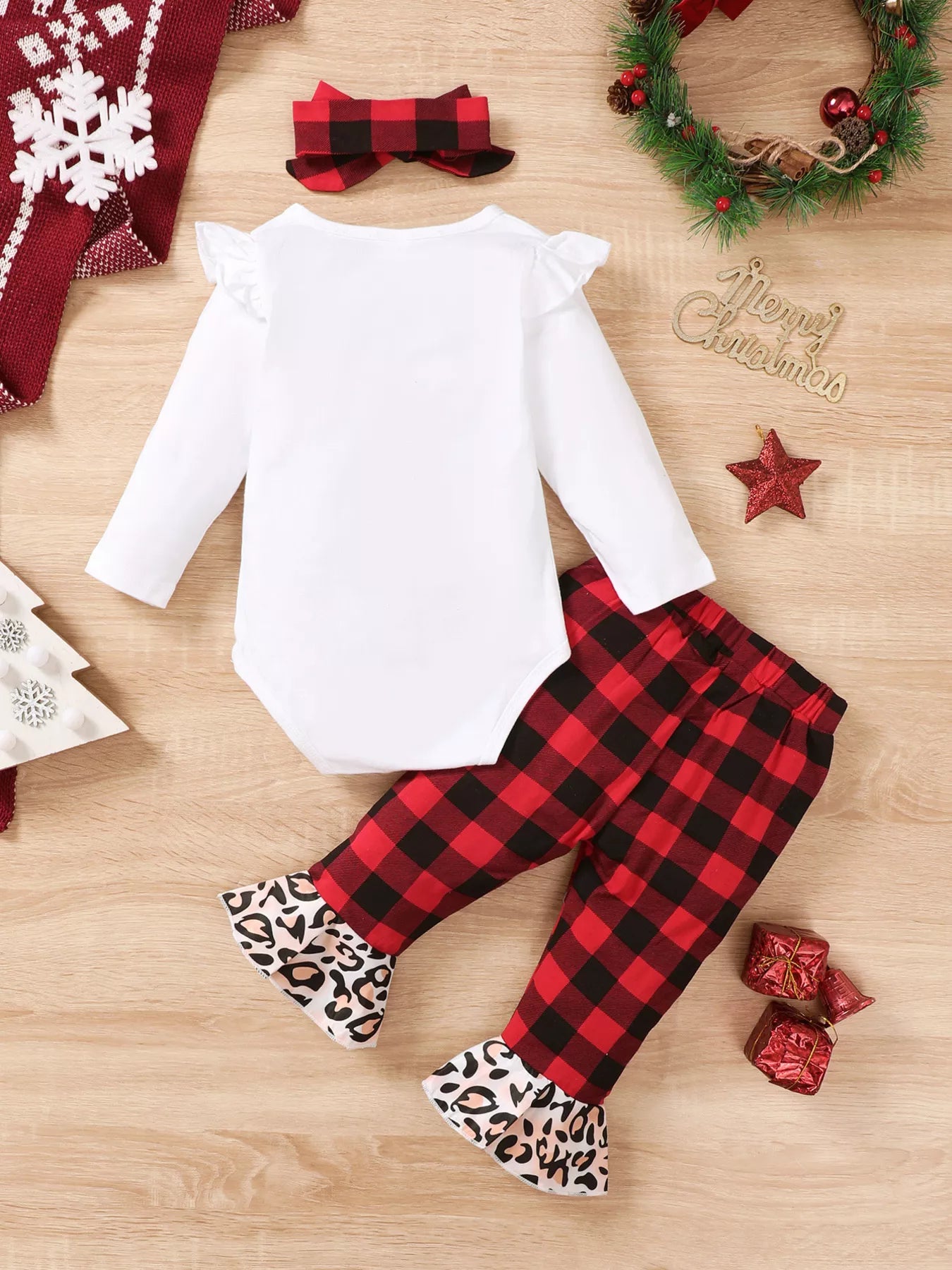 Baby girl wearing a Christmas tree graphic long sleeve top, red and black plaid ruffle pants and matching bow headband.