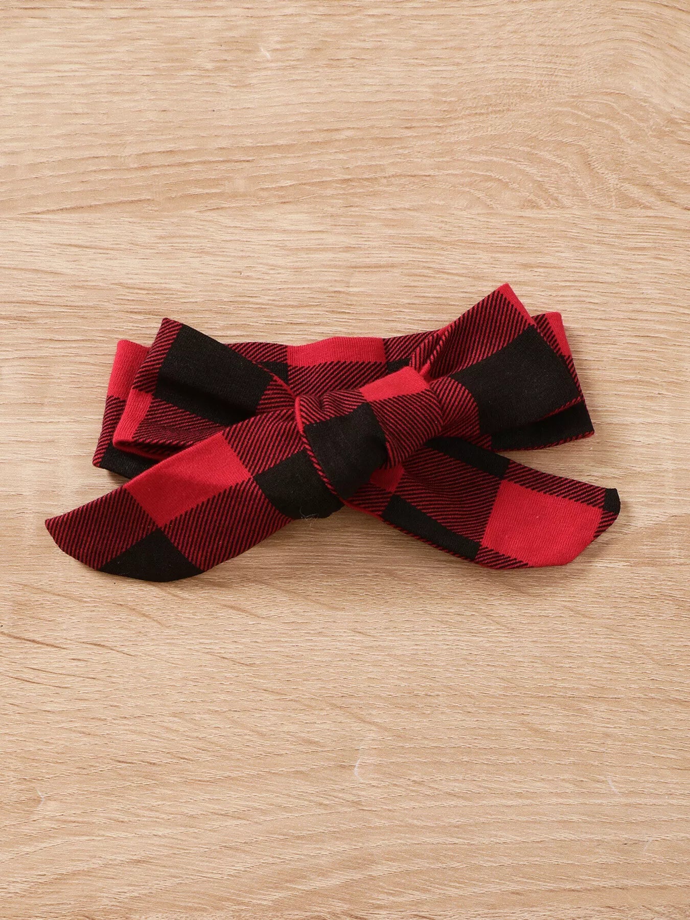 Baby girl wearing a Christmas tree graphic long sleeve top, red and black plaid ruffle pants and matching bow headband.