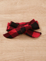 Baby girl wearing a Christmas tree graphic long sleeve top, red and black plaid ruffle pants and matching bow headband.