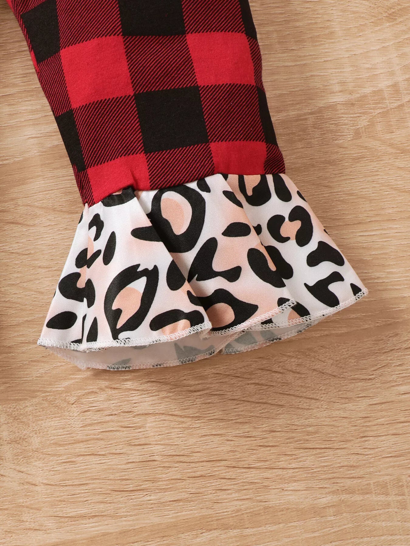 Baby girl wearing a Christmas tree graphic long sleeve top, red and black plaid ruffle pants and matching bow headband.