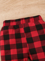 Baby girl wearing a Christmas tree graphic long sleeve top, red and black plaid ruffle pants and matching bow headband.
