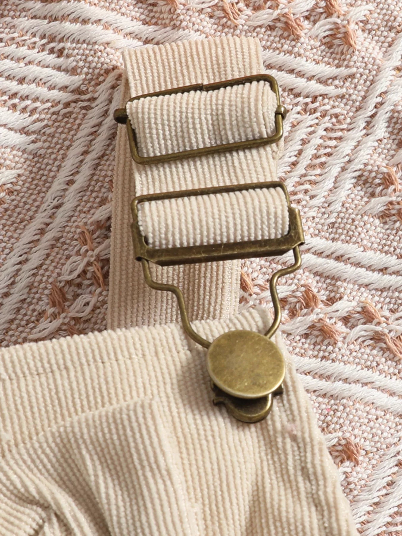 Baby girl three-piece outfit featuring a cream ribbed long-sleeve bodysuit with ruffled shoulders, apricot color bow-embroidered overalls and matching apricot bow headband.