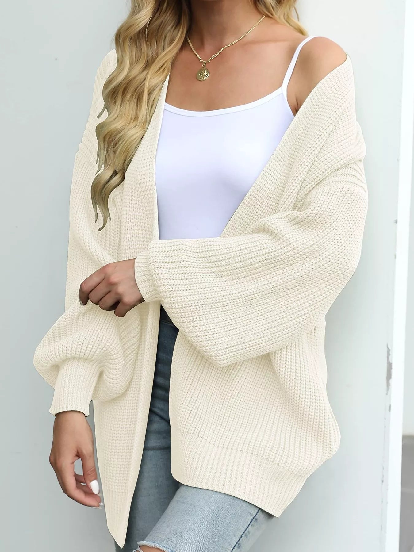 Women's oversized beige chunky knit open front cardigan with long balloon sleeves, soft textured sweater perfect for fall layering with jeans.