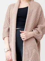 Women's khaki color chunky waffle knit open front cardigan with front pockets, cozy oversized fall sweater layered over a black top and leggings.