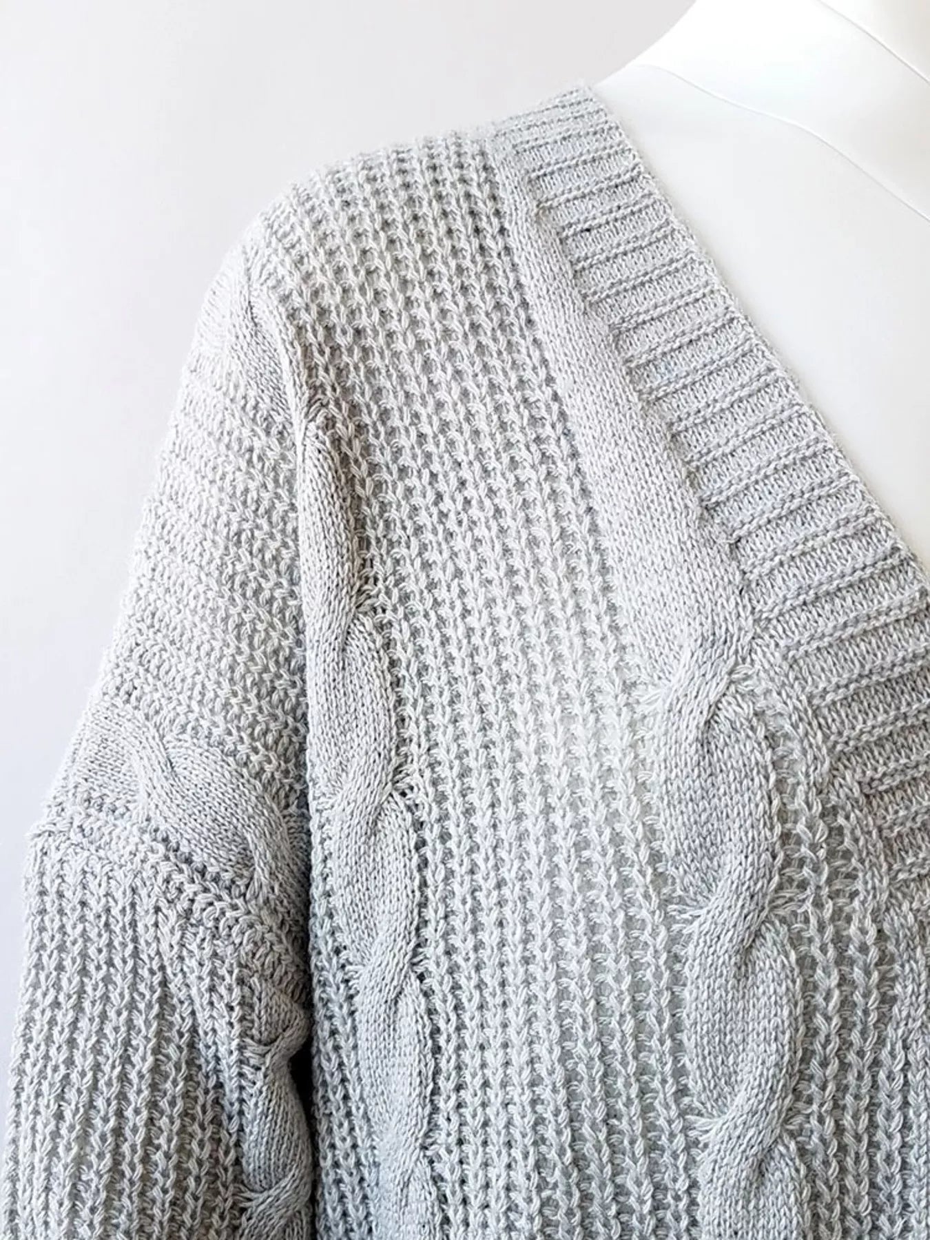 Women's chunky cable knit open front cardigan with front pockets in light gray. Cozy fall sweater perfect for layering with jeans, dresses, leggings, and boots.