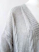 Women's chunky cable knit open front cardigan with front pockets in light gray. Cozy fall sweater perfect for layering with jeans, dresses, leggings, and boots.