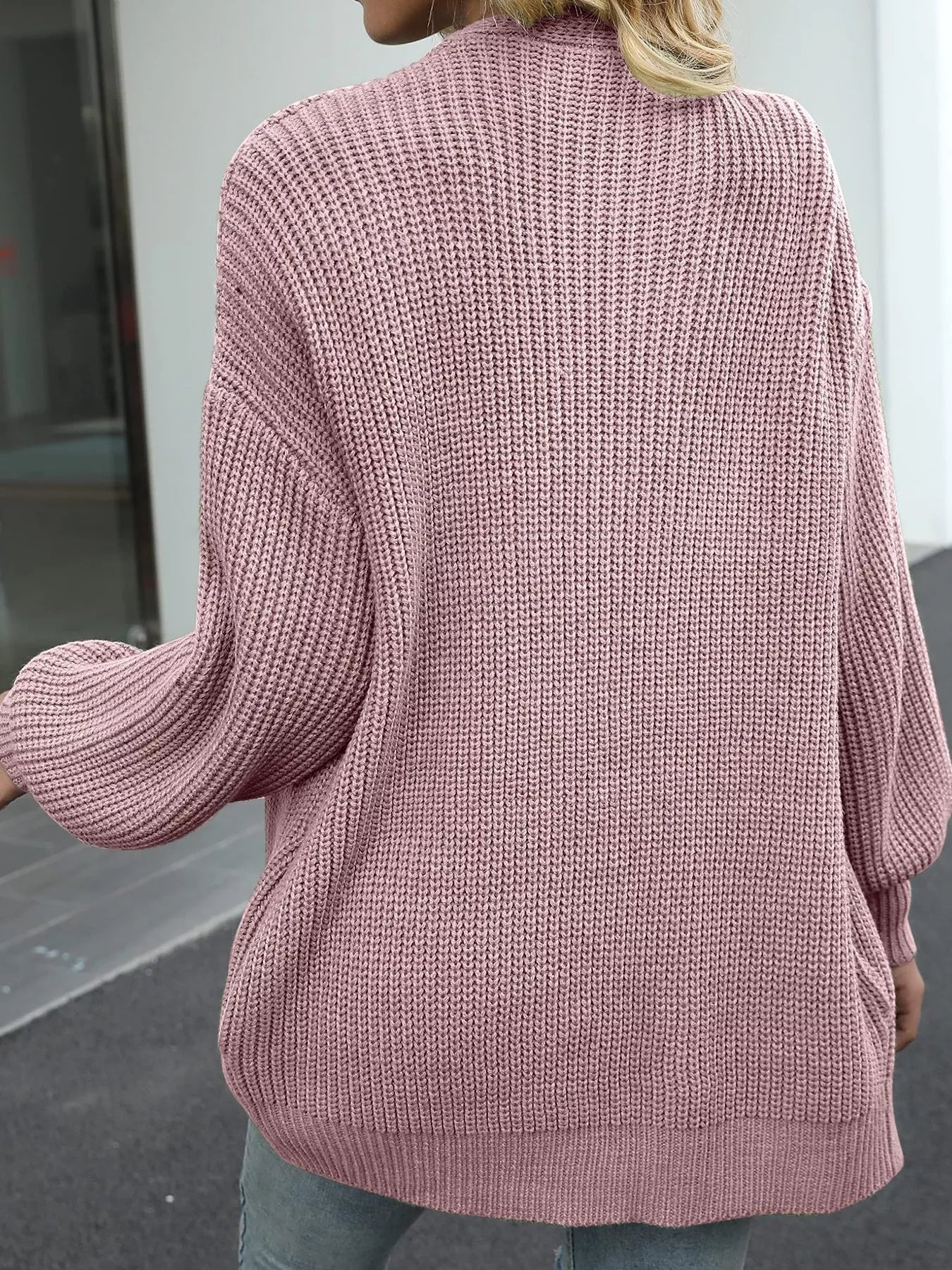 Women's oversized pink chunky knit open front cardigan with long balloon sleeves, soft textured sweater perfect for fall layering with jeans.