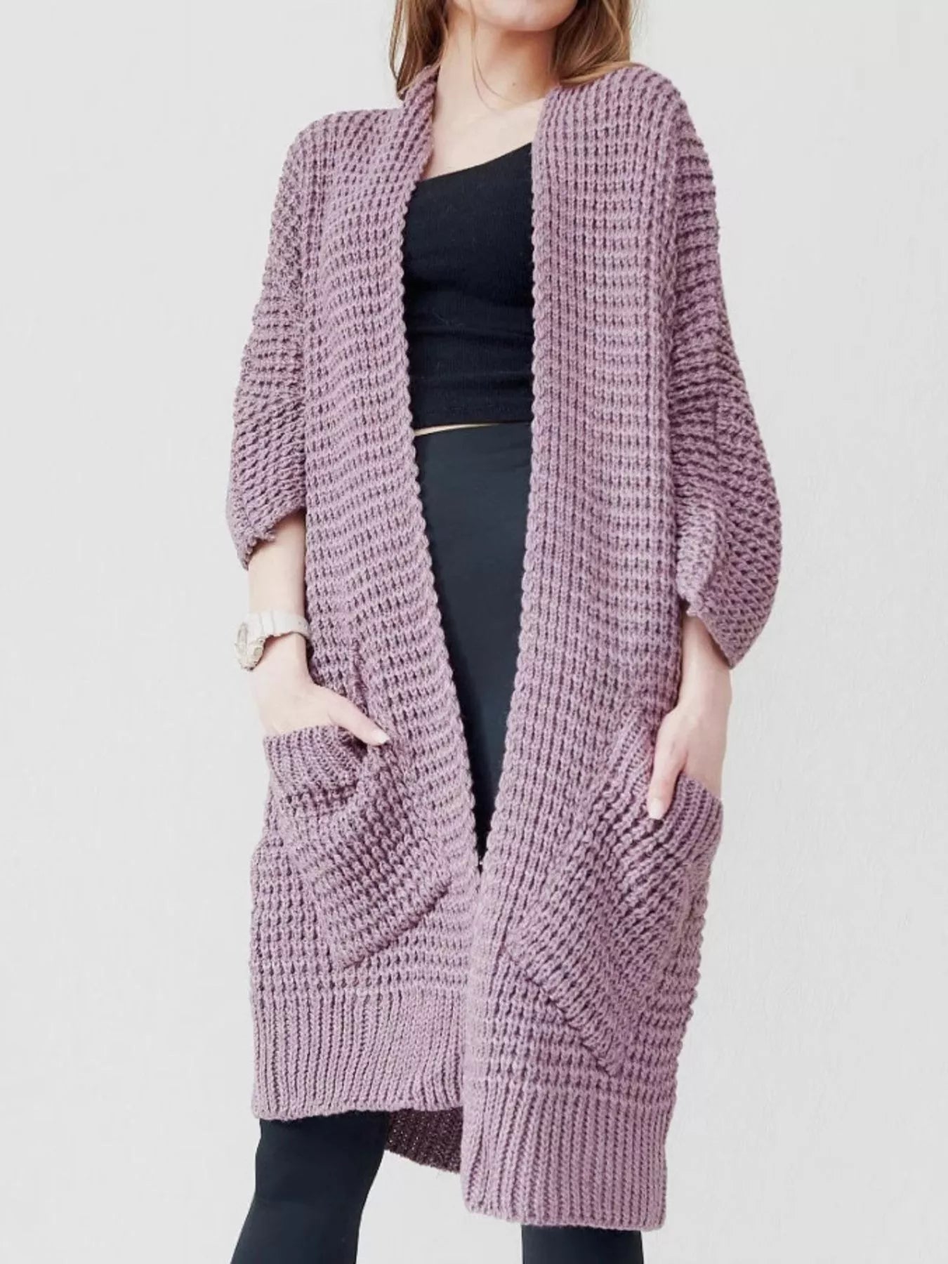 Women's purple chunky waffle knit open front cardigan with front pockets, cozy oversized fall sweater layered over a black top and leggings.