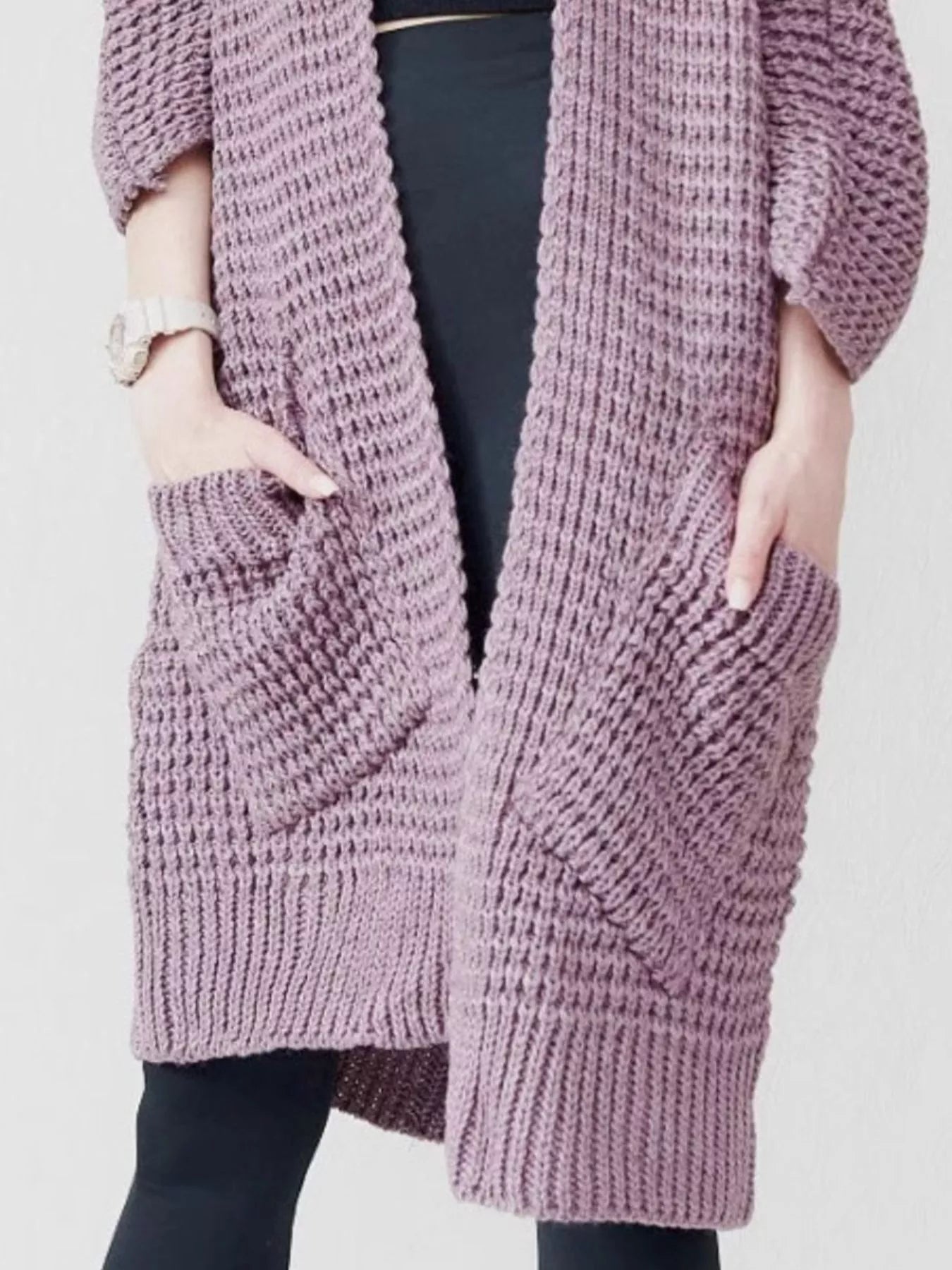 Women's purple chunky waffle knit open front cardigan with front pockets, cozy oversized fall sweater layered over a black top and leggings.