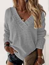 Woman wearing a cloudy blue V-neck long sleeve knit top with ribbed neckline and cuffs, styled with black denim shorts.
