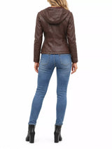 Woman wearing a coffee-brown faux leather moto jacket with detachable drawstring hood, front zipper, seam detailing and zippered pockets, paired with blue jeans.