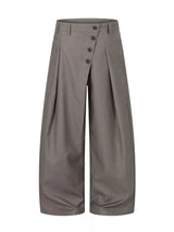 Men’s asymmetrical button wide-leg pants in coffee and black with pleated front and statement button detail.