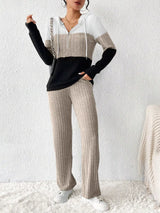 Woman wearing a dust storm, black and white color block half zip hooded top with matching ribbed-look pants.