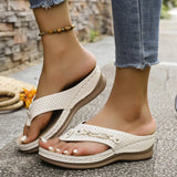 White sandals worn on feet with a stone wall background