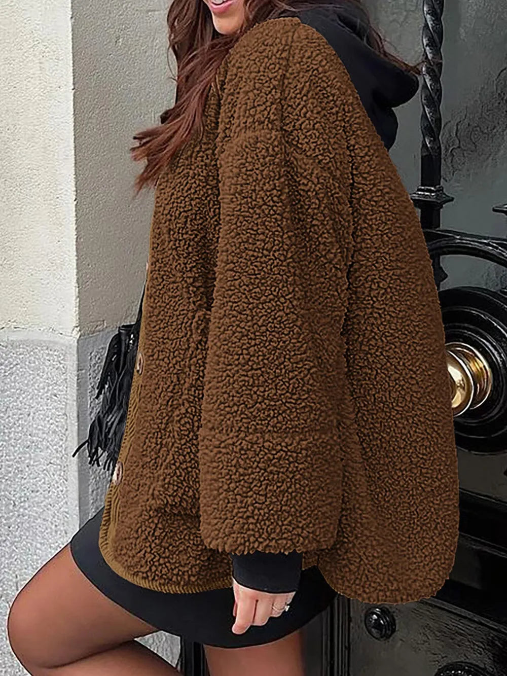 Women's brown textured sherpa jacket with long sleeves and relaxed silhouette, styled over a black hooded outfit.