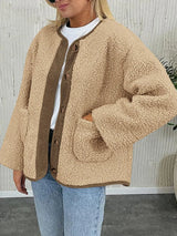 Women's tan sherpa jacket with contrasting ribbed trim, round neckline, front buttons, and patch pockets, layered over a cream sweater.