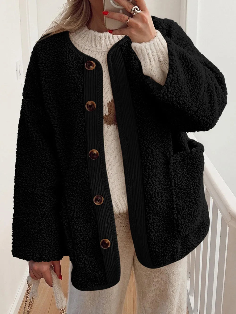 Women's black contrast button up sherpa jacket with pockets and long sleeves.