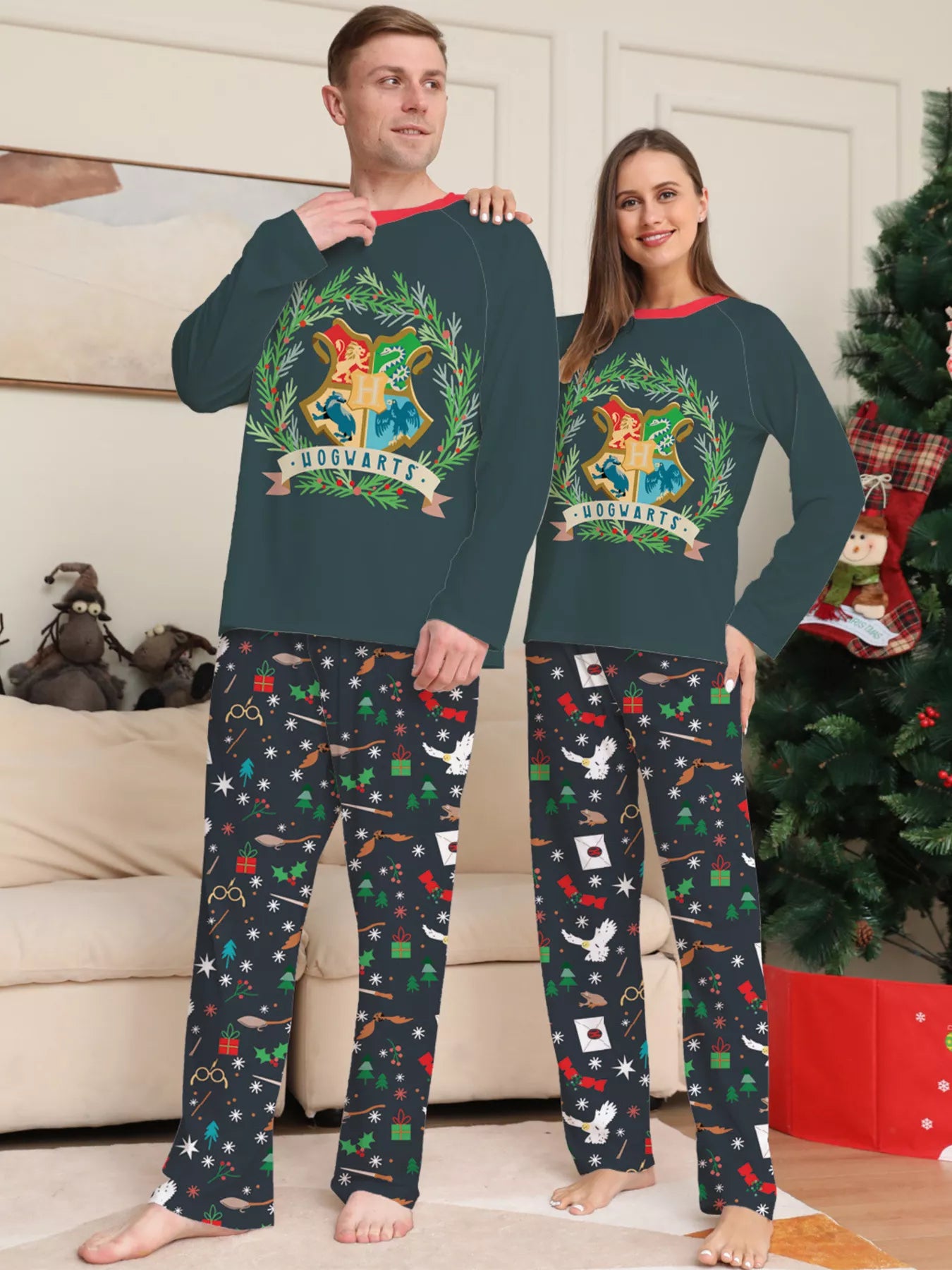 Family wearing matching dark green Hogwarts graphic Christmas pajama tops with coordinating navy holiday print pajama pants.