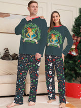 Family wearing matching dark green Hogwarts graphic Christmas pajama tops with coordinating navy holiday print pajama pants.