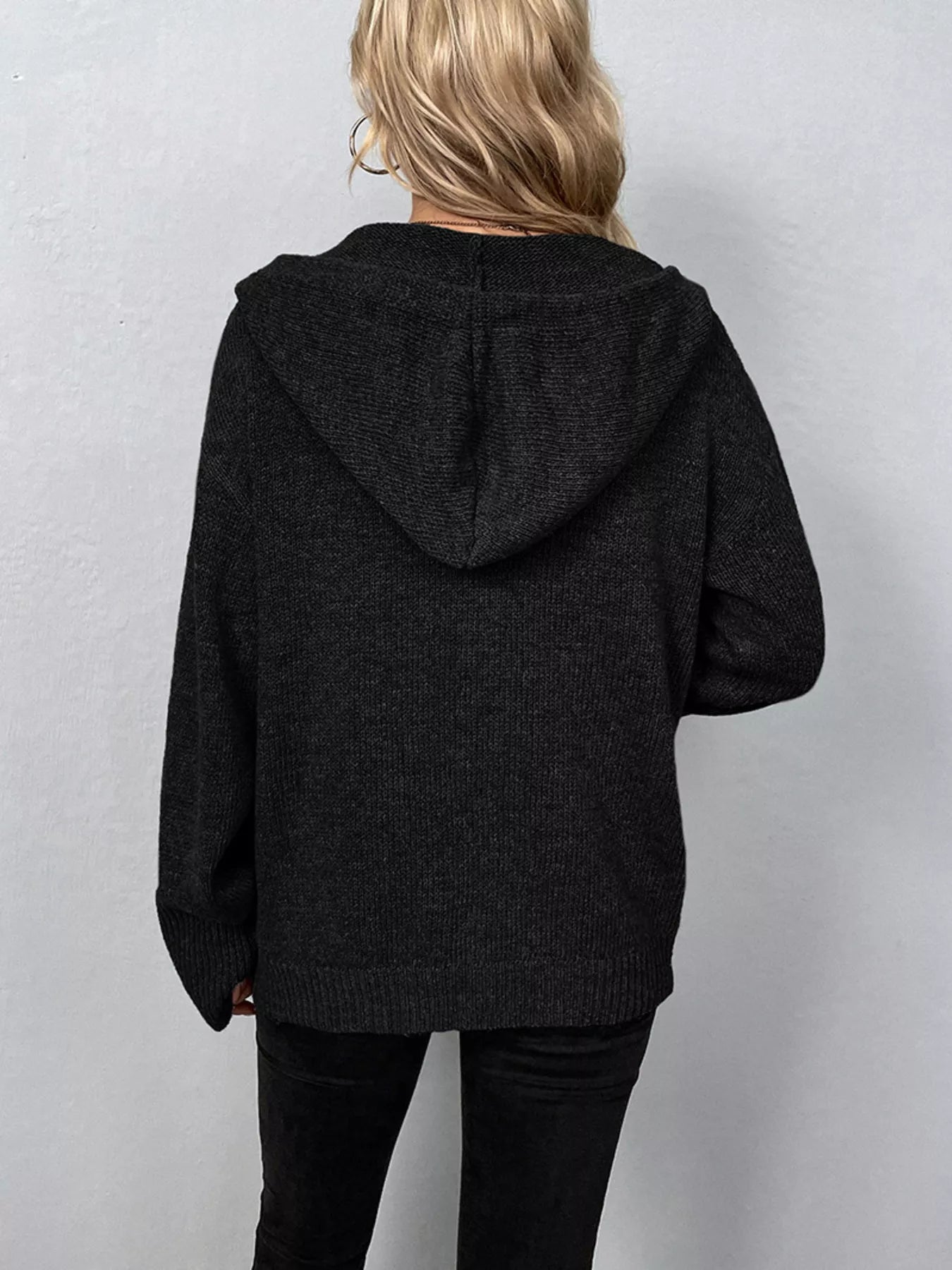 Women's black cozy knit hooded button-down cardigan with black buttons, soft lightweight sweater paired with black pants for casual fall style.