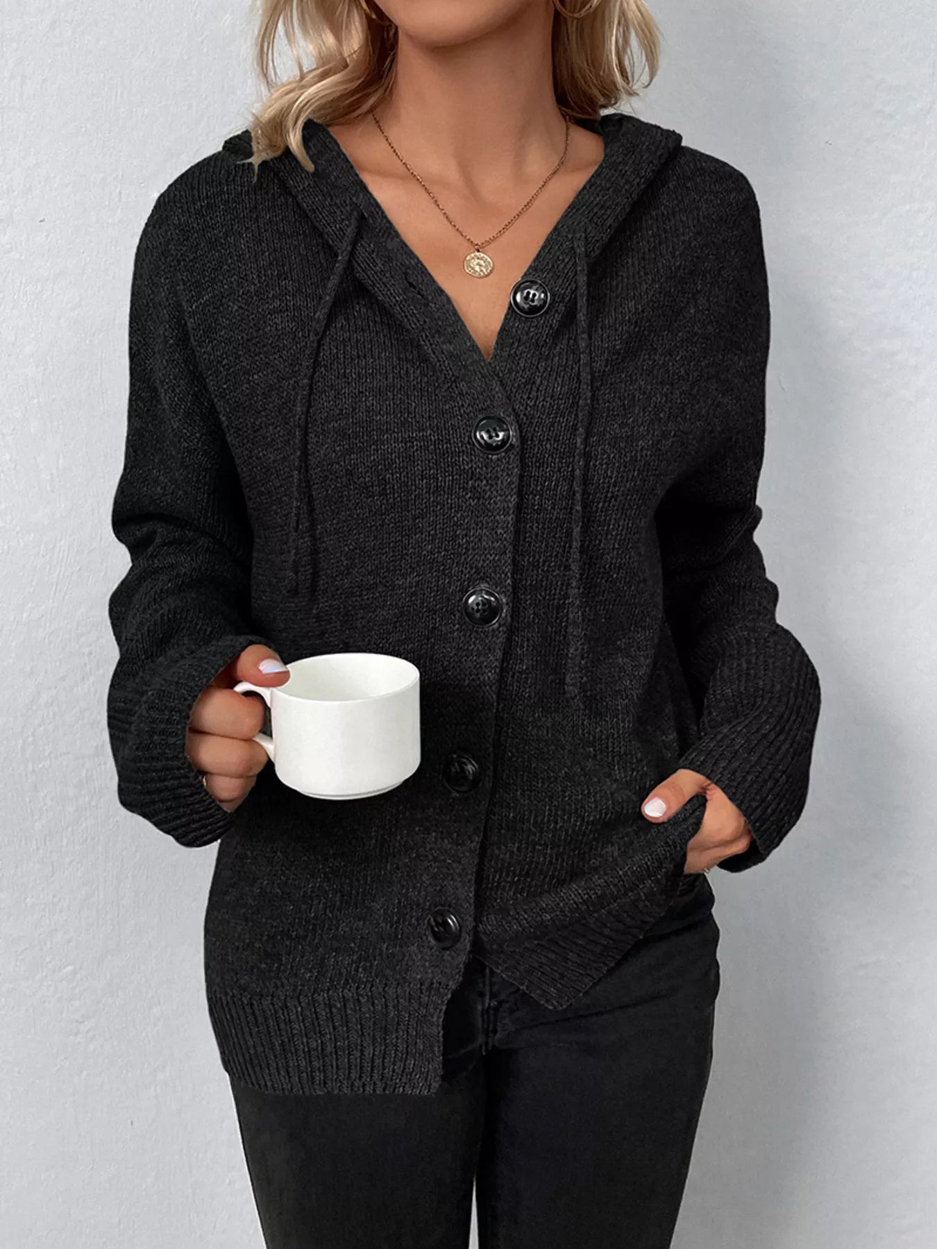 Women's black cozy knit hooded button-down cardigan with black buttons, soft lightweight sweater paired with black pants for casual fall style.