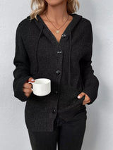 Women's black cozy knit hooded button-down cardigan with black buttons, soft lightweight sweater paired with black pants for casual fall style.
