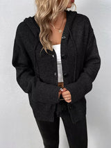 Women's black cozy knit hooded button-down cardigan with black buttons, soft lightweight sweater paired with black pants for casual fall style.