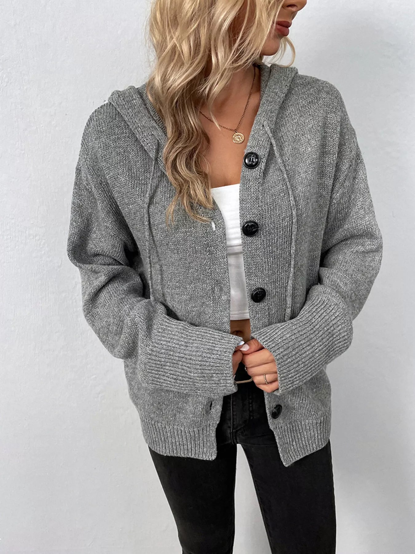 Women's gray cozy knit hooded button-down cardigan with black buttons, soft lightweight sweater paired with black pants for casual fall style.