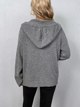 Women's gray cozy knit hooded button-down cardigan with black buttons, soft lightweight sweater paired with black pants for casual fall style.