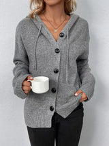 Women's gray cozy knit hooded button-down cardigan with black buttons, soft lightweight sweater paired with black pants for casual fall style.