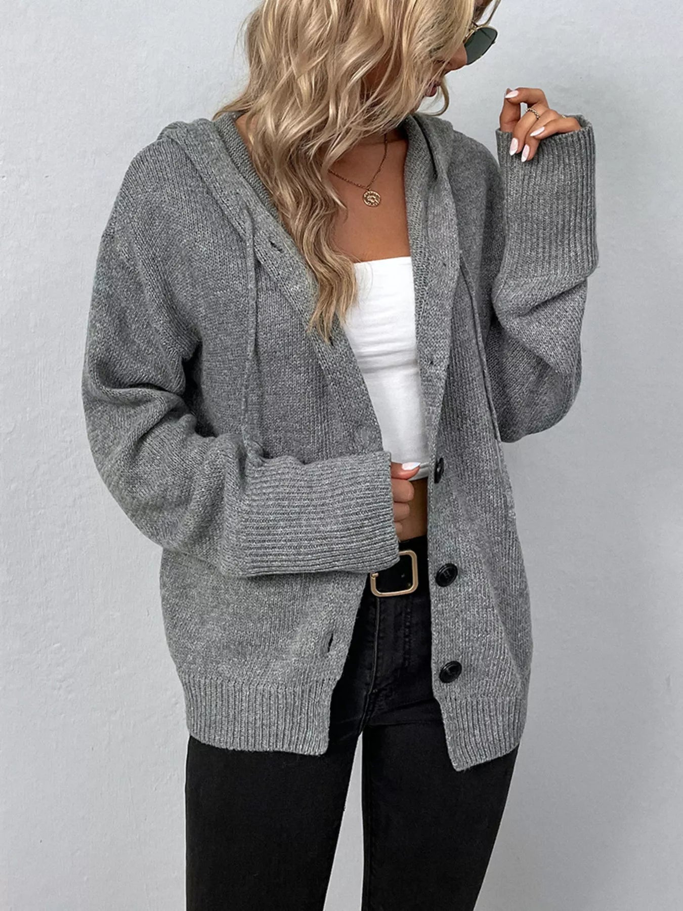 Women's gray cozy knit hooded button-down cardigan with black buttons, soft lightweight sweater paired with black pants for casual fall style.