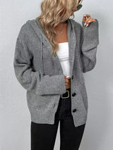 Women's gray cozy knit hooded button-down cardigan with black buttons, soft lightweight sweater paired with black pants for casual fall style.