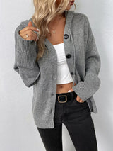 Women's gray cozy knit hooded button-down cardigan with black buttons, soft lightweight sweater paired with black pants for casual fall style.