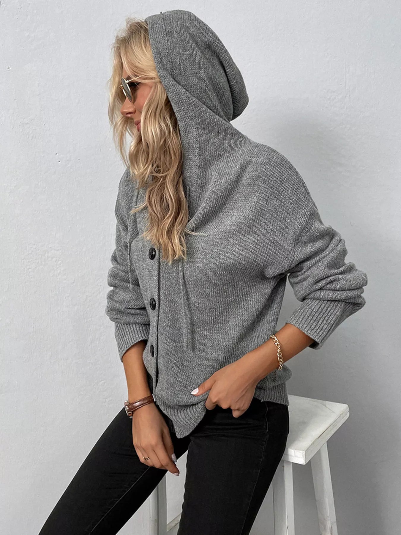 Women's gray cozy knit hooded button-down cardigan with black buttons, soft lightweight sweater paired with black pants for casual fall style.