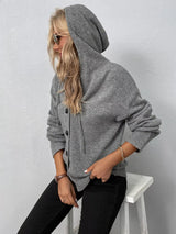 Women's gray cozy knit hooded button-down cardigan with black buttons, soft lightweight sweater paired with black pants for casual fall style.