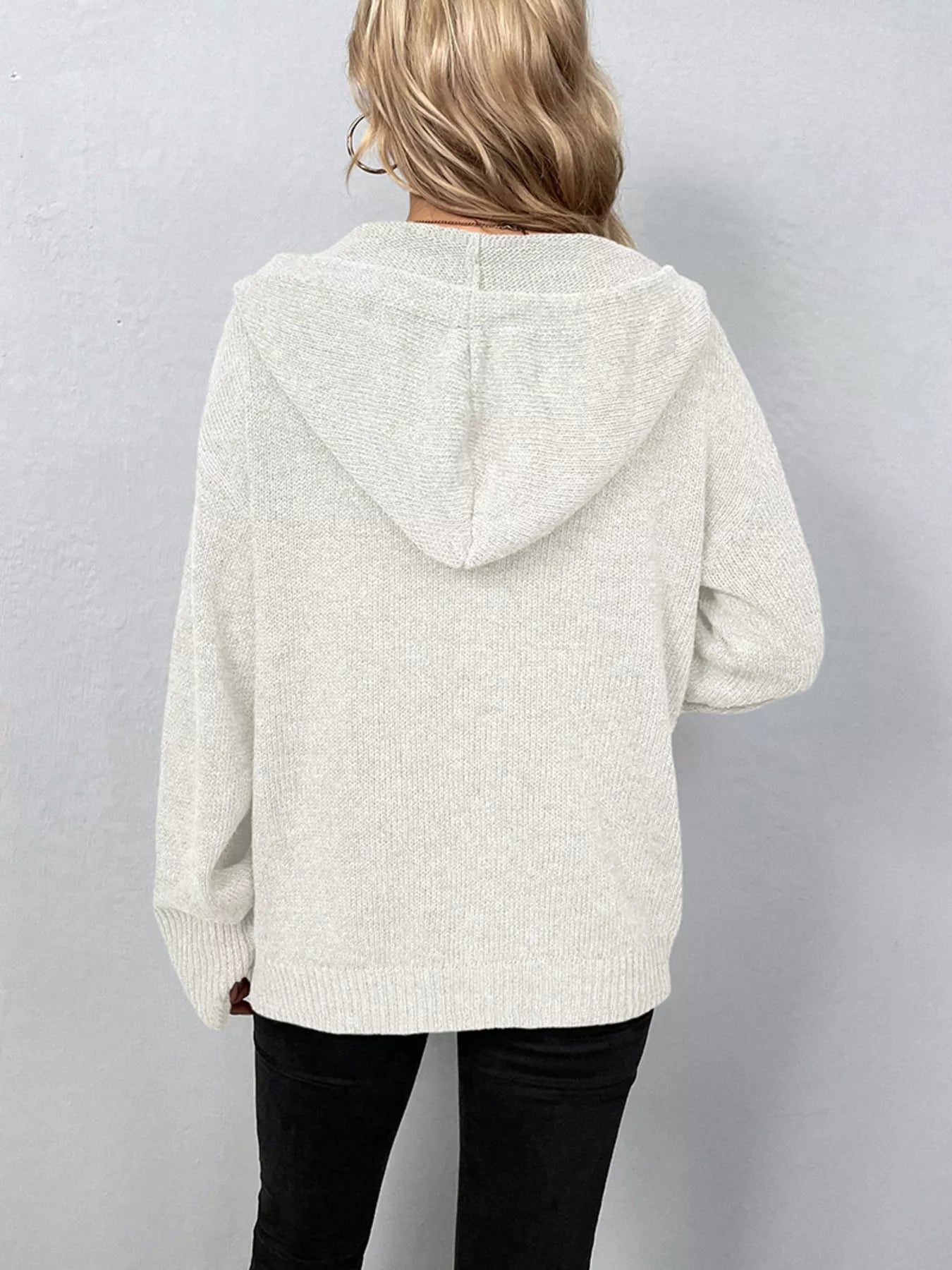 Women's white cozy knit hooded button-down cardigan with black buttons, soft lightweight sweater paired with black pants for casual fall style.