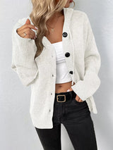 Women's white cozy knit hooded button-down cardigan with black buttons, soft lightweight sweater paired with black pants for casual fall style.
