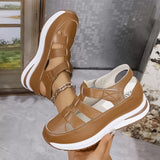 Brown sandals with white soles held by a hand against a neutral background