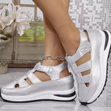 Silver sandals with white soles worn by a person, with a blurred indoor background.