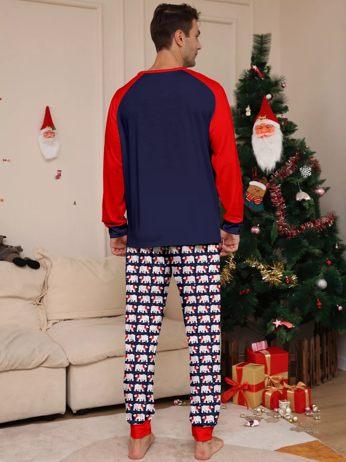 Dad wearing matching Christmas pajamas with navy tops, red raglan sleeves, festive Christmas tree lettering, and coordinating printed pants. 