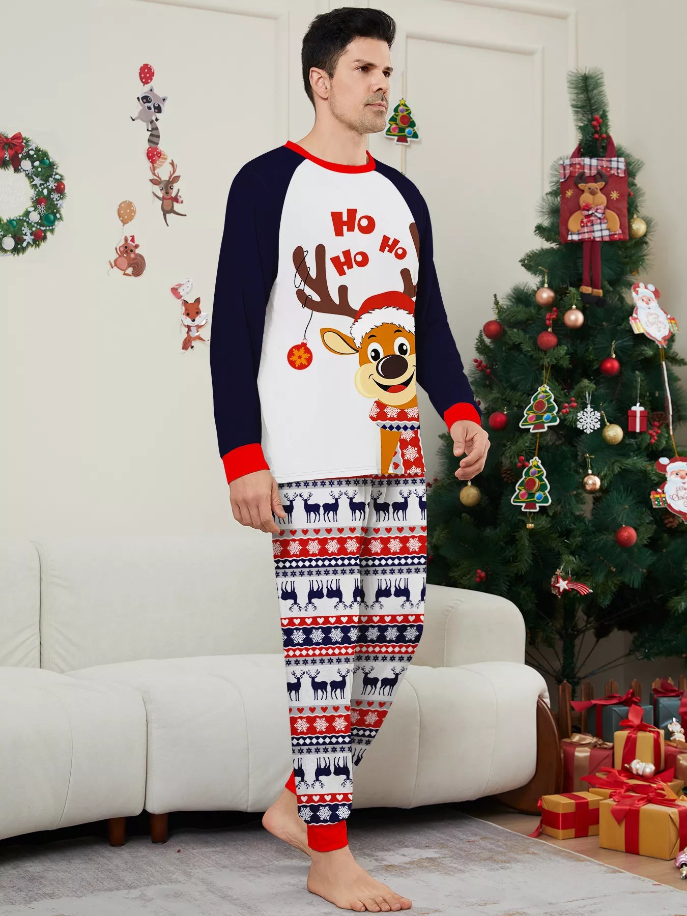 Dad wearing matching Christmas reindeer pajamas with navy sleeves, red trim, smiling Santa-hat reindeer graphics and festive patterned pants.