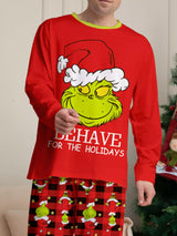 Man modeling matching red Grinch-themed Christmas pajamas with festive graphic tops and red and black character-print pants.